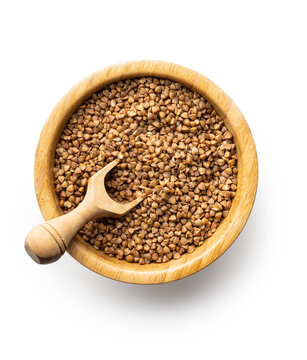 Uncooked buckwheat grain in scoop isolated on white background. © Jiri Hera