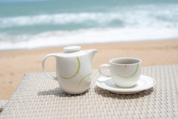cup and pot of tea on wood table sea background.