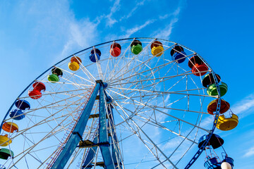 Ferris wheel in an amusement park close-up. Ferris wheel against the blue sky, bottom view