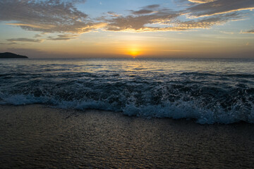 The sun sets over the horizon on the Sea with wave