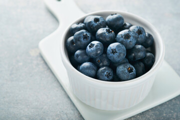 Blueberry. White bowl of fresh blueberries on grey stone background table. Tasty ripe blueberries. Place for text. Food background. Top view.