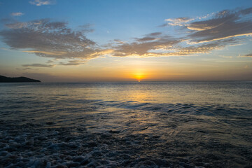 The sun sets over the horizon on the Sea with wave