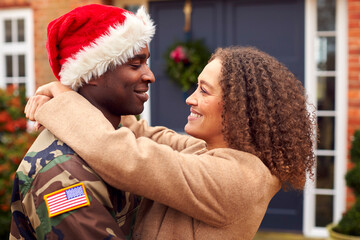 American Soldier In Uniform Wearing Santa Hat Returning Home On Christmas Leave Hugging Woman