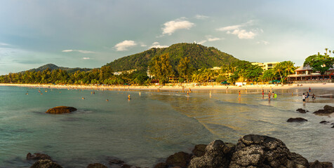 People and tourists resting on beach. Panorama of asian coastline of Kata Beach on Phuket Island in Thailand