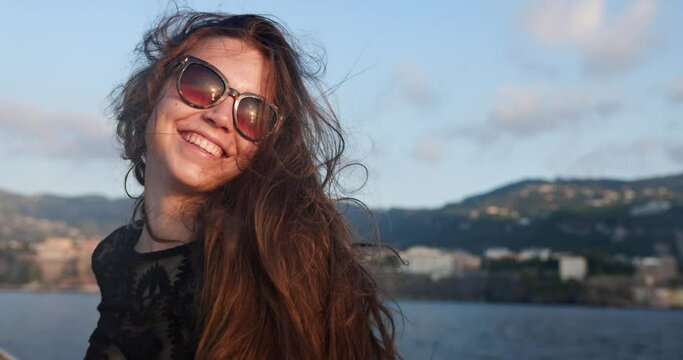 Pretty woman laughing with sunset reflected in sunglasses
