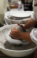 manos de artesano moldeando cerámica en horno alfarero artesanal  - obrazy, fototapety, plakaty