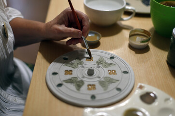 mano pintando la decoración de cerámica artesanal con pincel 