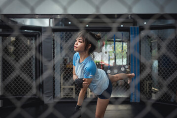 A Filipino Muay Thai athlete stretches her leg in the octagon ring cage before her match.