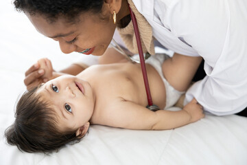 doctor pediatrician examining and kissing baby on the bed