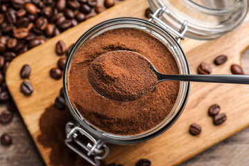 Instant coffee and spoon above glass jar on wooden table, flat lay