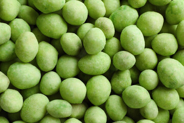 Tasty wasabi coated peanuts as background, top view