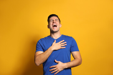 Handsome man laughing on yellow background. Funny joke