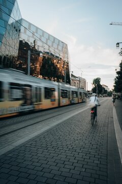 Long Exposure Of The Freiburg City In Germany With A Train Passing By And A Person Driving A Bicycle