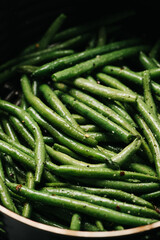 Raw, and seasoned green beans in an air fryer