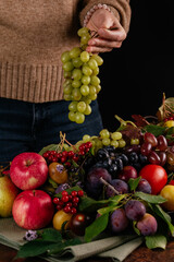 a girl holds green grapes against the background of autumn fruit