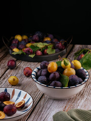 fresh ripe plums in a light ceramic plate on a wooden background