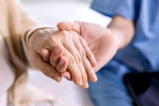 Close-up senior Asian woman hand with her caregiver helping hands holding together, Caregiver visit at home. Home health care and nursing home concept.