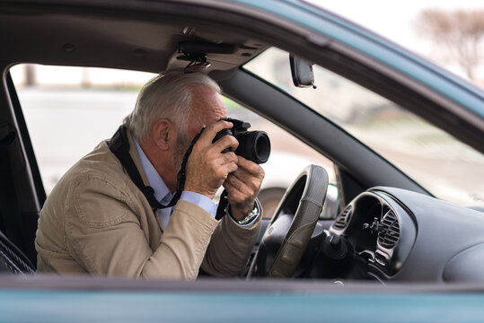 Senior man photographing with his camera while sitting in the car