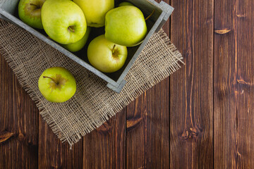 Yellow apples in a crate on a wooden background