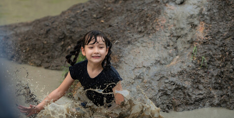 Little girls have fun playing in the mud in the community fields