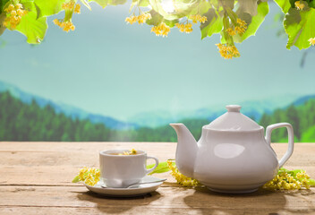 Linden tea on the garden table. Teapot and cup on wooden table. Linden flowers and hot lime tea. Herbal teas concept.