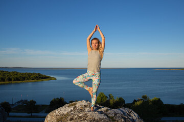 yoga in the mountains  woman in tree pose with sea background 