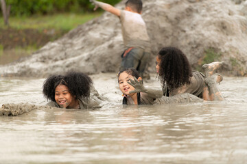 Little girls have fun playing in the mud in the community fields - obrazy, fototapety, plakaty