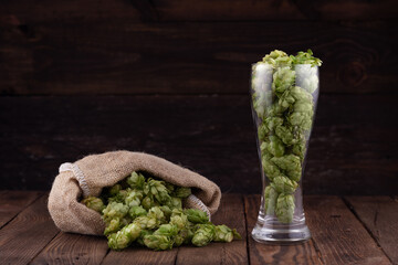 Glass of fresh green hops on wooden table