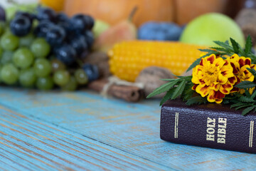 A closeup of a closed Holy Bible Book with flowers and fresh autumn food in the background....