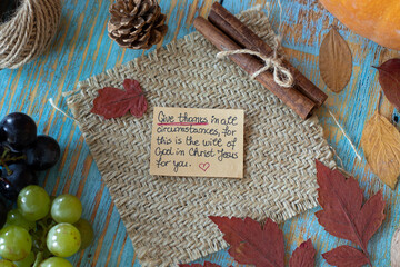 Fototapeta na wymiar Handwritten message to give thanks to God Jesus Christ on a note in a vintage autumn setting with grapes, pumpkin, and dry leaves. Christian thanksgiving, gratitude, and praise.