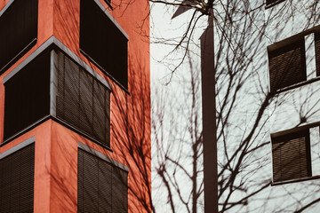 Blick auf Hausfassade in rot und weiß in der Stadt mit Fenstern und dem Schatten eines Baumes