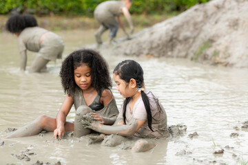 Little girls have fun playing in the mud in the community fields