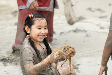 Children have fun playing in the mud in the community fields and catching a frog in a muddy field.