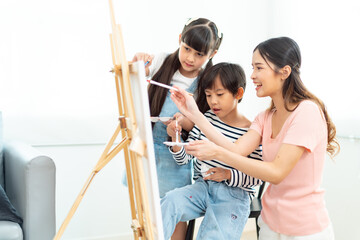 Young arts teacher with paintbrush consulting one of her pupils at lesson of painting.The adorable...