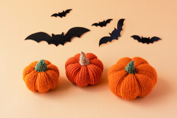 Knitted orange pumpkins and black bats on an orange background, autumn composition, front view. Halloween concept.