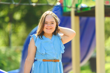 portrait of trisomie 21 child girl outside having fun on a playground