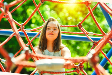 portrait of trisomie 21 child girl outside having fun on a playground