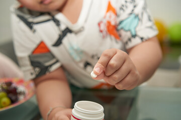 boy hold pill by fingertips show medicine tablet