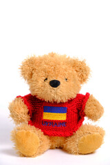 Soft toy on a white background, bear red jacket with flag Ukraine depicted on it.