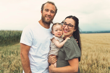 happy family with baby girl are playing in wheat field.