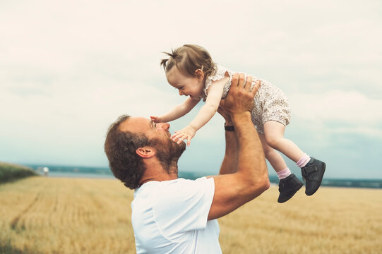 happy baby child girl and father are playing in wheat field.