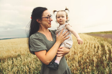 happy baby child girl and mother are playing in wheat field.
