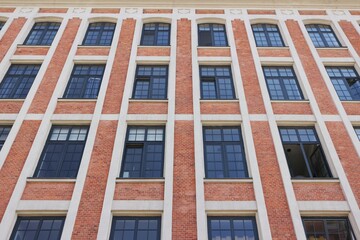Rows of windows in the red brick wall of a renovated former factory building in Zyrardow.