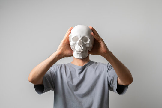 man holding a white skull in front of face on halloween holidays