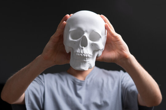 man holding a white skull in front of face on halloween holidays
