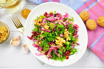 Healthy vegetarian Salad with pomegranate, walnuts and lettuce leaves.