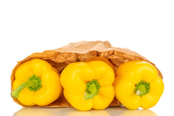 Three sweet peppers of bright yellow color in a paper bag, macro, isolated on a white background.