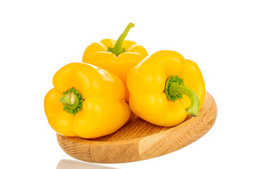 Three sweet peppers of bright yellow color on a wooden tray, macro, isolated on a white background.