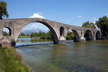 Fototapeta na wymiar The Bridge of Arta. A stone bridge that crosses the Arachthos river in the west of the city of Arta in Greece. Sunny day with blue sky