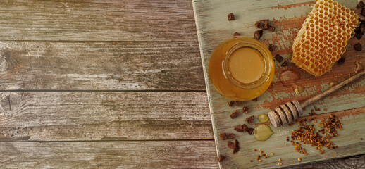 Honey background. Sweet honey in a glass jar and a honey spoon on a wooden table. Banner. Copy space for your text